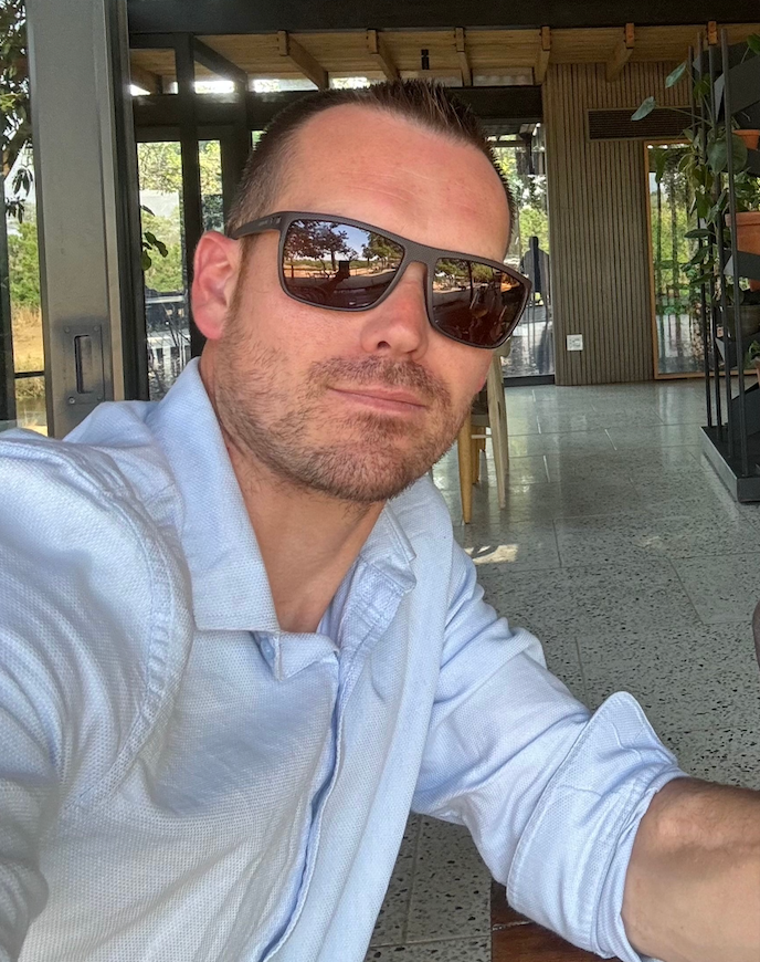 Man wearing sunglasses and a light blue shirt in an indoor setting